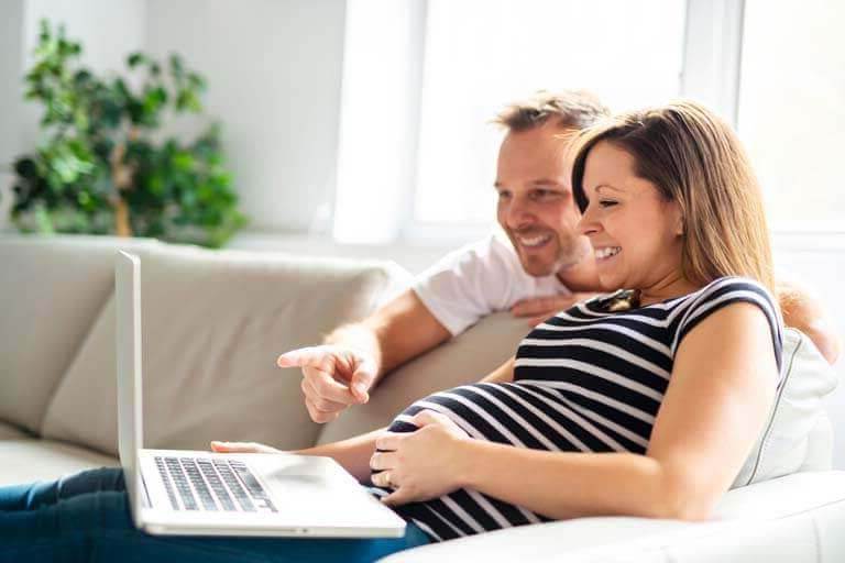 Zwanger stel achter laptop